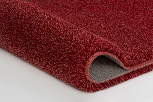 Roter, flauschiger Teppich mit rutschfester Unterseite, ideal für Wohn- und Schlafzimmer.