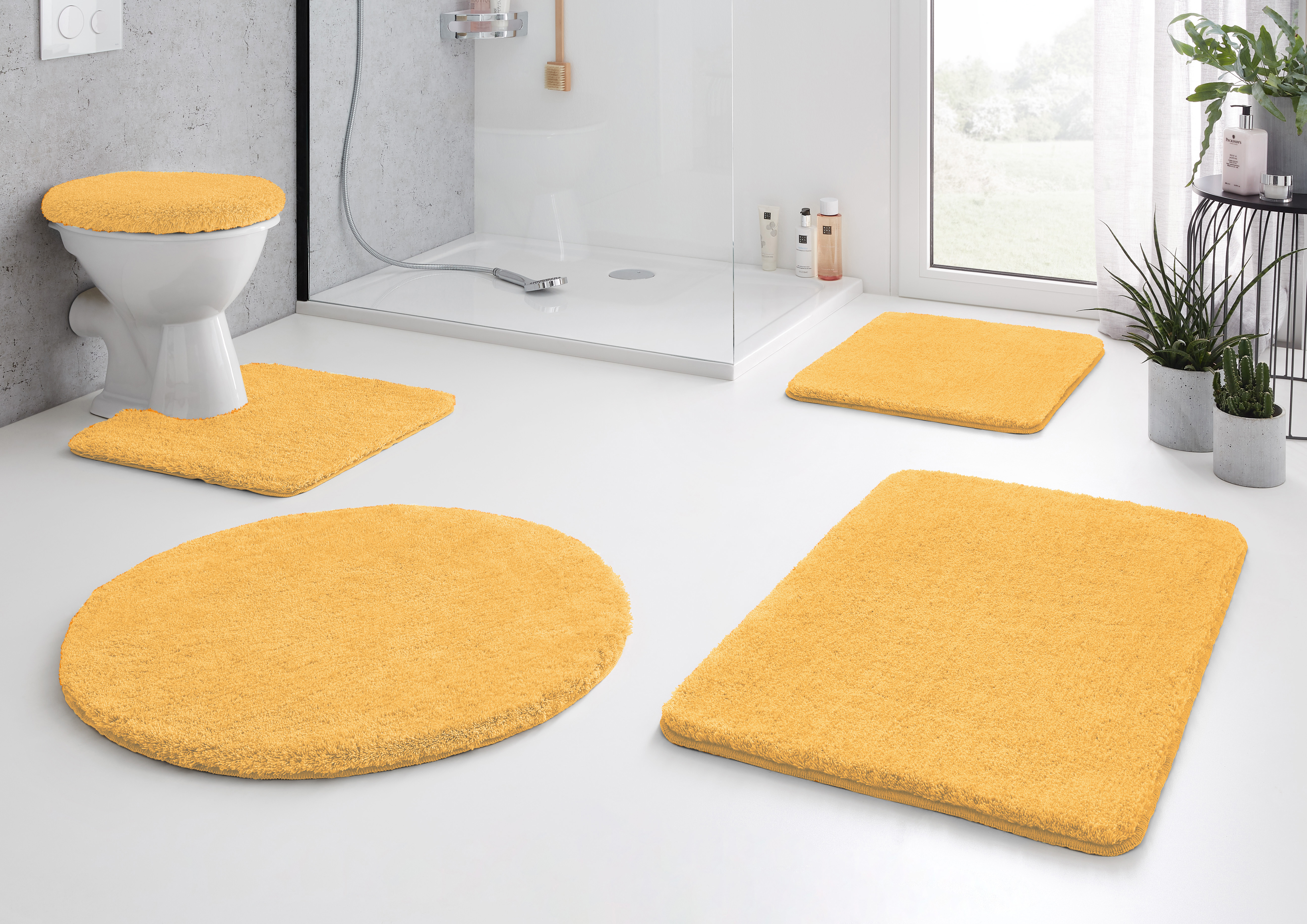 Produkte von Kleine Wolke: Gelbe Badematten-Set, bestehend aus WC-Deckelbezug, Duschvorleger, WC-Vorleger und zwei rechteckigen Matten.