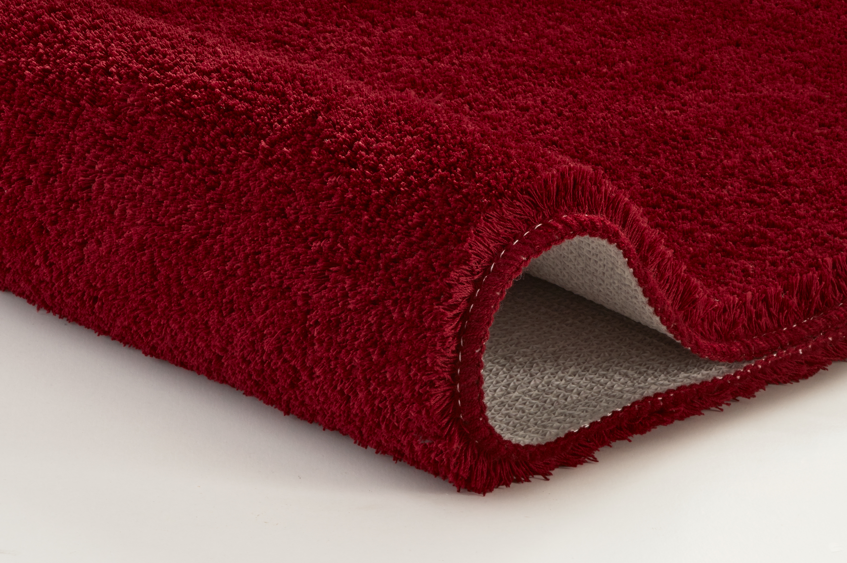 Roter, flauschiger Teppich mit rutschfester Unterseite, ideal für Wohn- und Schlafzimmer.